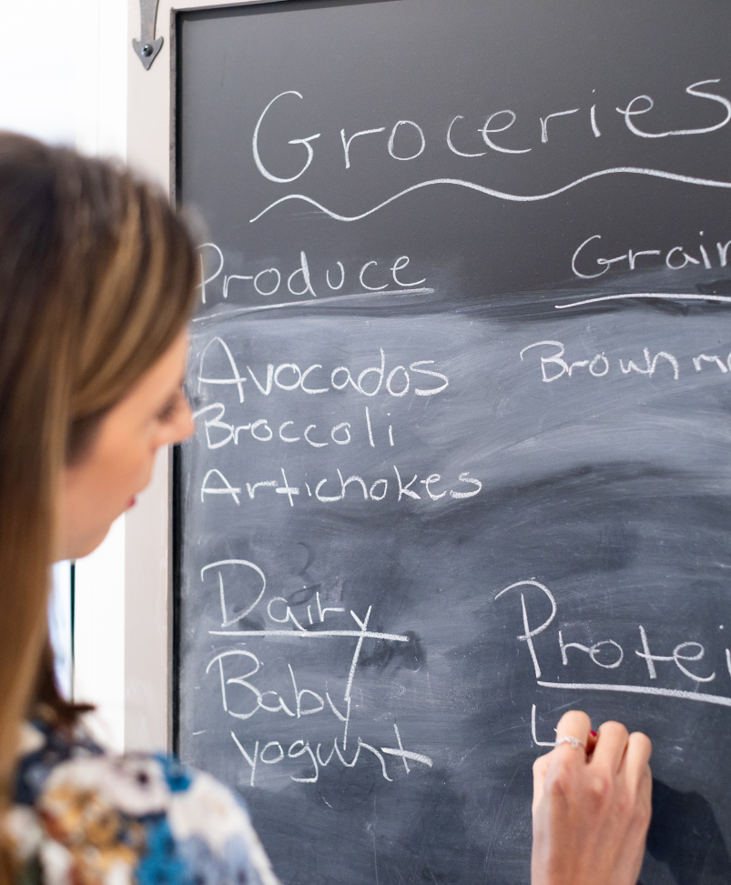Writing out a grocery plan with healthy high fiber foods on a chalkboard